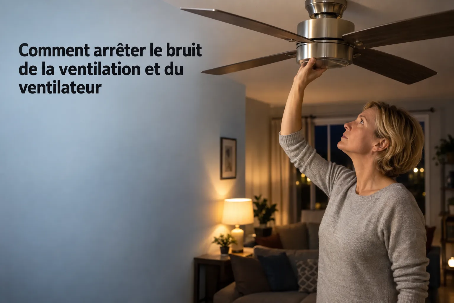 Une femme ajuste une lampe au plafond d’un ventilateur, dans un salon éclairé.